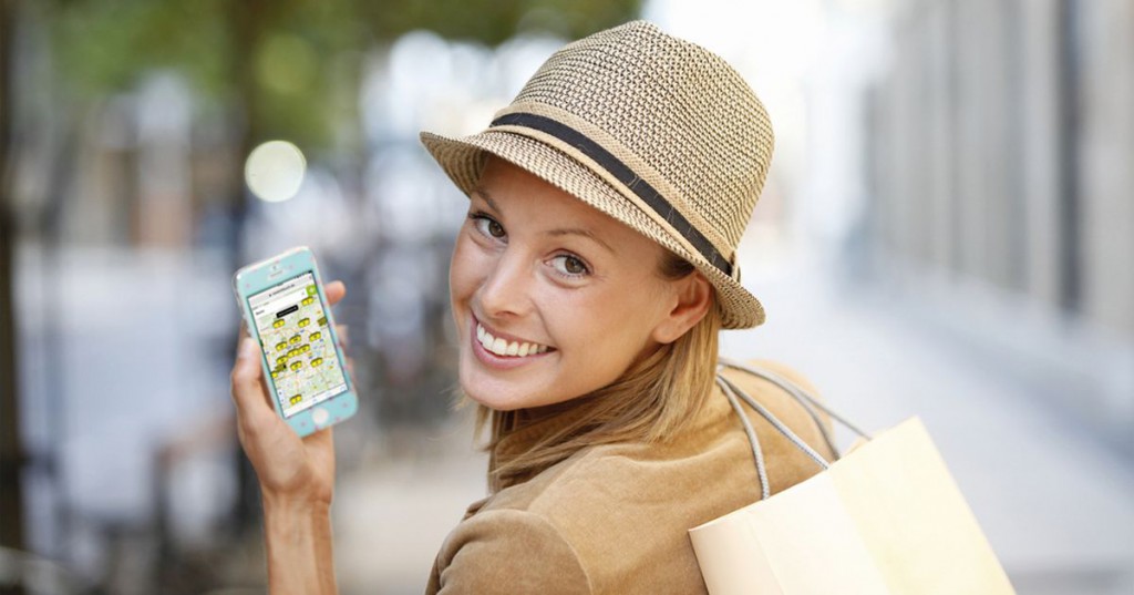 Smiling shopping girl using smartphone in town